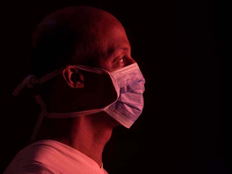 Coronavirus, side portrait of african american man with protective mask. COVID-19 concept. Studio shot on dark background with copyspace