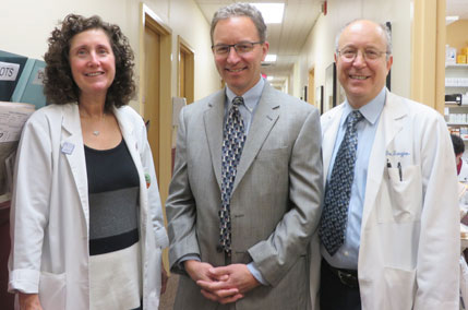 Two physicians and a man standing in a hallway